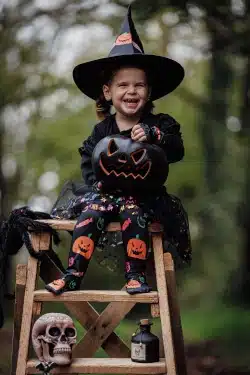 jeune fille assise sur une échelle en costume d'halloween