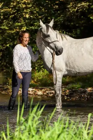 Une cavalière au niveau de la tête de son cheval blanc
