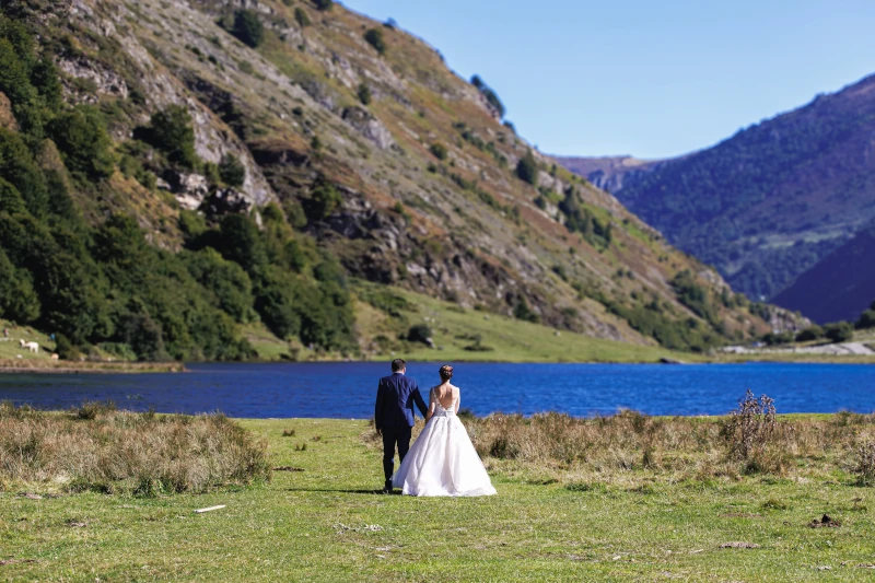 couple de mariés de dos devant une montagne et un lac